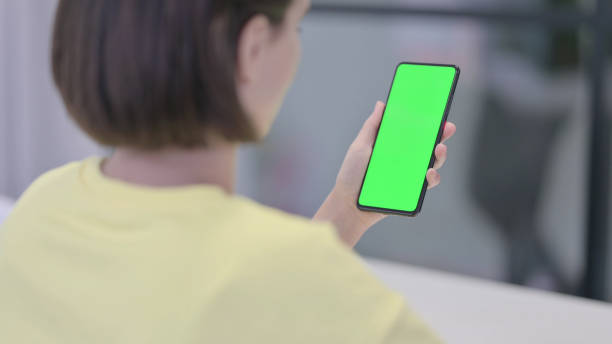 istock Young Woman Holding Smartphone with Green Chroma Screen 1421151544