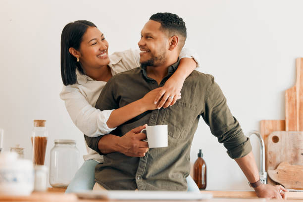 istock Happy, coffee and loving couple bonding and having fun while spending time together at home. Smiling, in love and carefree couple hugging and sharing a romantic moment while enjoying the weekend 1421152618