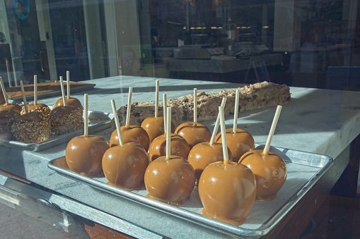 Tray of caramel apples on display in candy shop window. View from street.