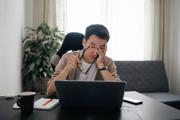 istock Middle aged tired asian man working at home with laptop. 1421164445