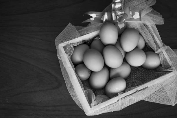 istock Chicken eggs basket on wooden background (white and black) 1421165416