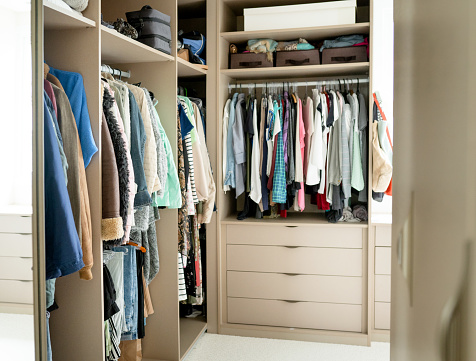 Clothing sitting on shelves and hanging from racks in the large walk-in closet in a contemporary home
