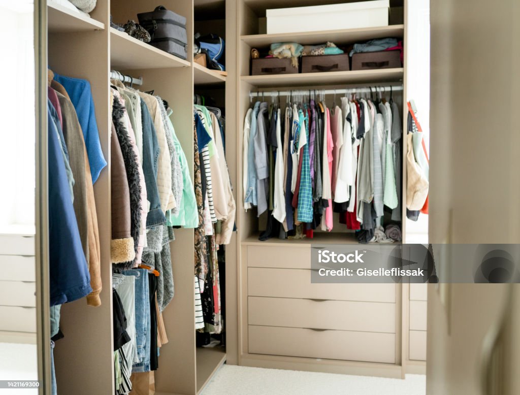 Walk-in closet full of clothing in a modern  home Clothing sitting on shelves and hanging from racks in the large walk-in closet in a contemporary home Closet Stock Photo