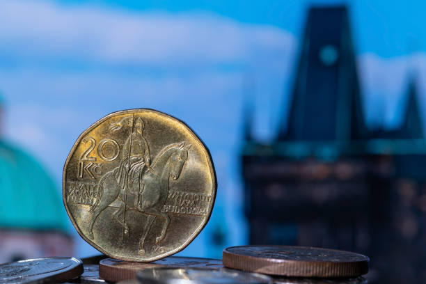 a 20 czk coin and other coins against the background of out-of-focus fragments of prague buildings - czech culture currency wealth coin imagens e fotografias de stock