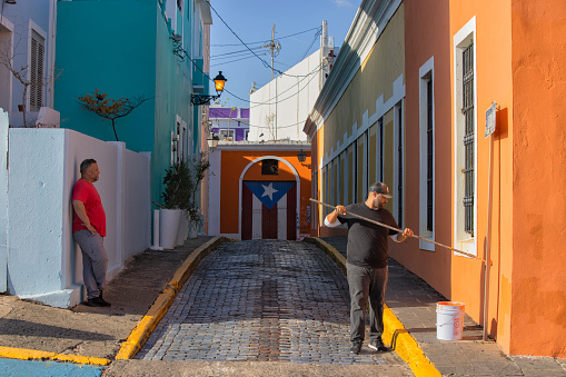 Man painting the wall of a colorful building, Old San Juan, Puerto Rico