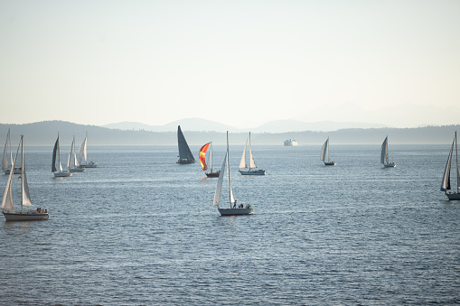 Bodrum,Mugla, Turkey. April 16,  2023: sailor team driving sail boat in motion, sailboat wheeling with water splashes, mountains and seascape on background. Sailboats sail in windy weather in the blue waters of the Aegean Sea, on the shores of the famous holiday destination Bodrum