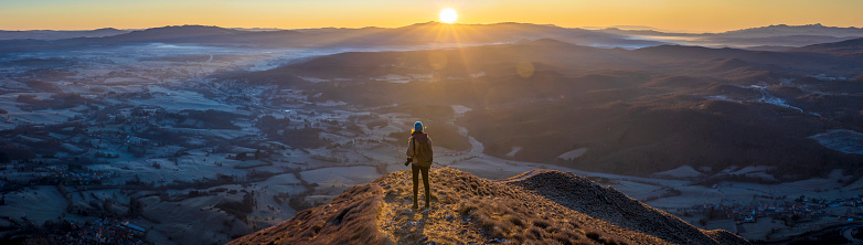 Panoramic of a Female Hiker Photographer Enjoying Moment of Sunrise over Winter Vipava Valley from Top of Nanos Mountain in Slovenia