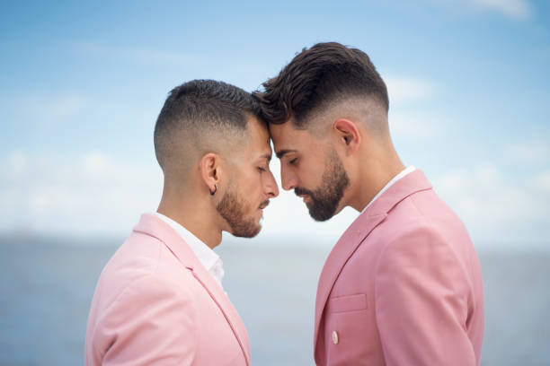 背景として海を持つ愛情のこもったゲイカップル - gay man homosexual men kissing ストックフォトと画像