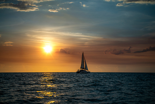 Young couple enjoys sailing in the tropical sea at sunset on their yacht.