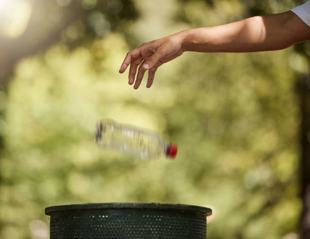 istock One unknown mixed race woman throwing a plastic bottle in a bin to conserve the planet earth and recycle. Hispanic woman choosing to toss litter in the trashcan. Protect the environment, keep clean 1421184651