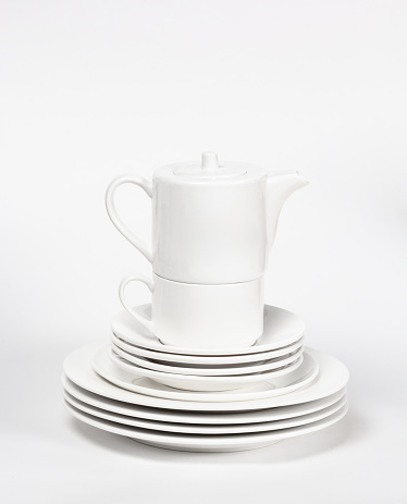 Set of white dishes with plates, cup and teapot on white background
