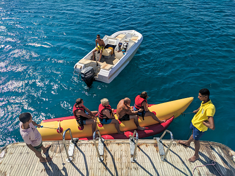 Hurghada, Egypt - October 1, 2021: People are sitting on the water attraction banana boat waiting for a ride on the red sea.