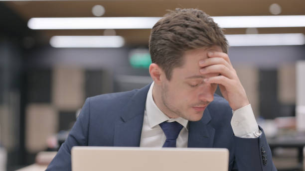 istock Upset Businessman with Headache Sitting at Work 1421190035