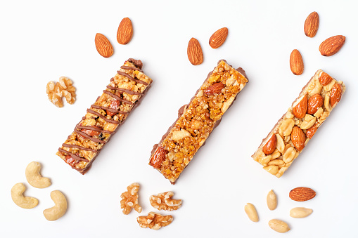Protein bars and nuts on white background top view close up.