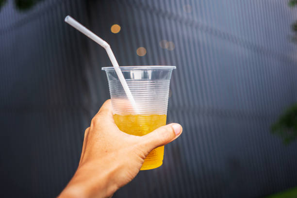 istock Human hand raised and holding up iced drink to the sky on pattern background 1421194563