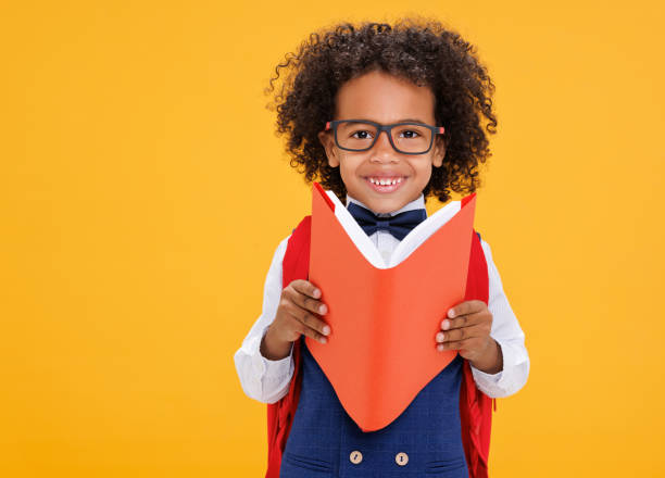 istock Happy ethnic schoolboy playing with book 1421194714