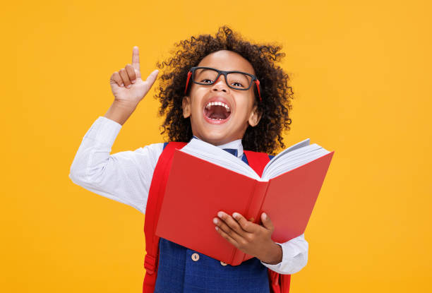 istock Smart ethnic schoolboy in glasses reading book 1421194784