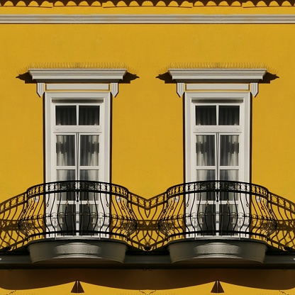perfect symmetrical pair of traditional rectangular windows with ornate wrought iron curved balcony