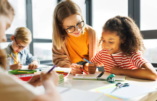 istock Teacher helping children with schoolwork 1421195561