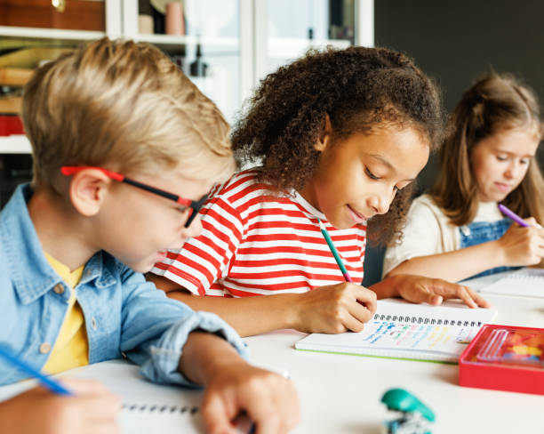 istock Cheerful ethnic girl solving test with classmates 1421195642