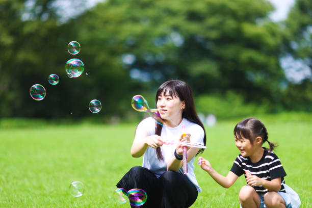 istock Mother and daughter having fun in park with Soap Bubbles 1421195929