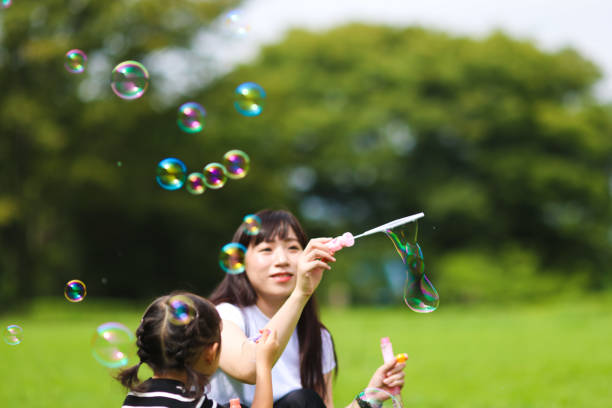 istock Mother and daughter having fun in park with Soap Bubbles 1421195941