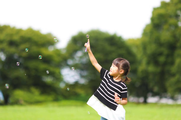 istock Mother and daughter having fun in park with Soap Bubbles 1421195958