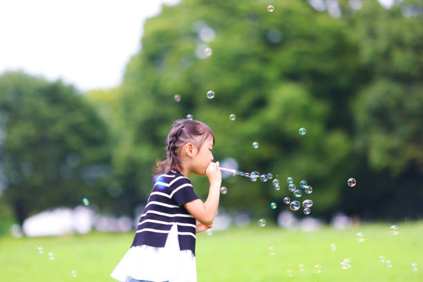 istock Mother and daughter having fun in park with Soap Bubbles 1421196014