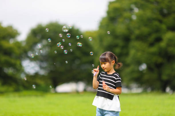istock Mother and daughter having fun in park with Soap Bubbles 1421196018