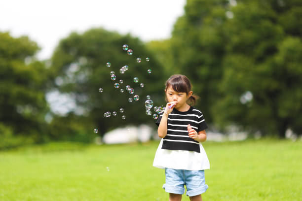 istock Mother and daughter having fun in park with Soap Bubbles 1421196026