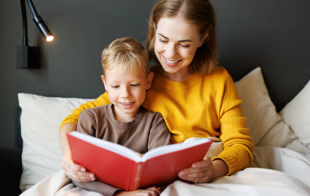 istock Happy mother and son reading book together on bed 1421196041