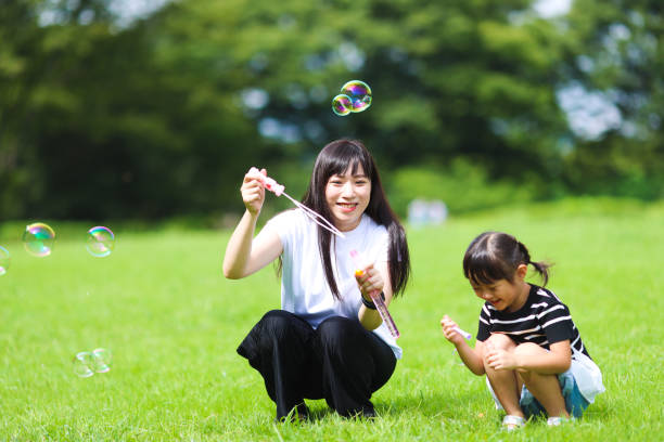 istock Mother and daughter having fun in park with Soap Bubbles 1421196134