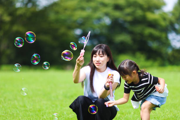 istock Mother and daughter having fun in park with Soap Bubbles 1421196149
