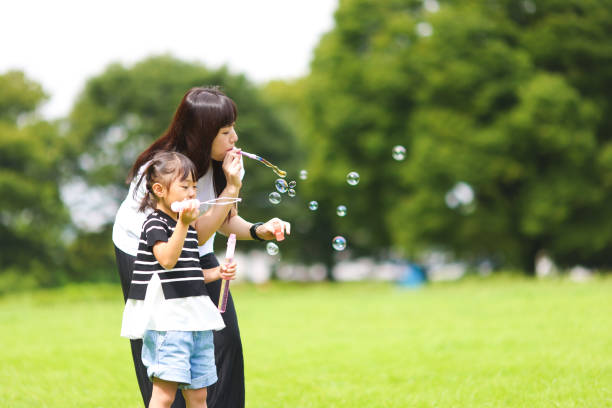 istock Mother and daughter having fun in park with Soap Bubbles 1421196183