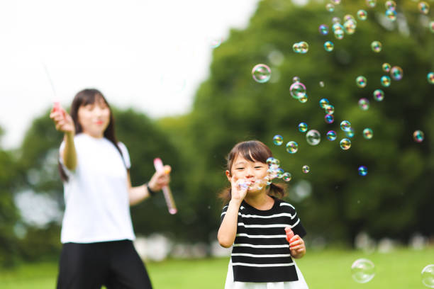 istock Mother and daughter having fun in park with Soap Bubbles 1421196223
