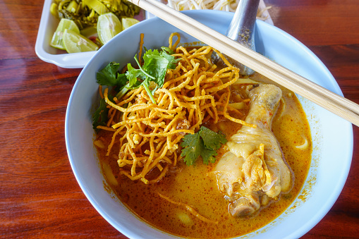 Northern Thai curry noodles with chicken, egg noodle in chicken curry or Khao Soi recipe. Traditional Thai cuisine, the mixture that tinted with tumeric and release the noble aroma of black cardamom.