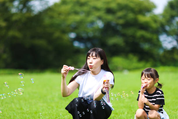 istock Mother and daughter having fun in park with Soap Bubbles 1421196228