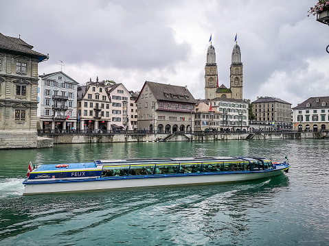 Zurich, Switzerland - September 8, 2019: tourists  boat in front of Grossmunster Cathedral with River Limmat in Zurich