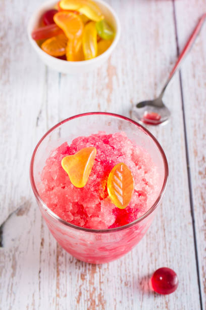 istock Red shaved ice snow cone with syrup and sweets in glasses on the table. Vertical view. Closeup 1421197889