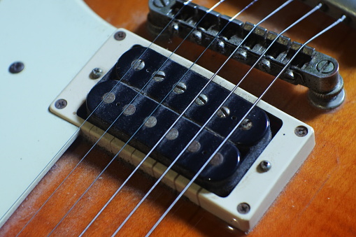 Close Up to the Bridge and single Pickup on body part of Sunburst 4 string jazz bass guitar isolated on white background.