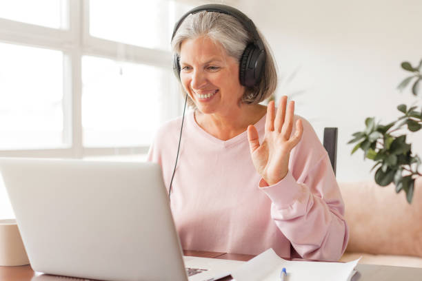 istock Middle aged businesswoman using earphone while sitting behind her laptop 1421200439