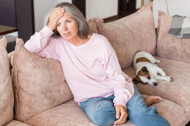 istock Sad pensive middle age woman looking down depressed sitting on the sofa 1421200441