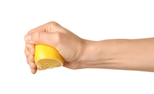istock Woman squeezing lemon half on white background, closeup 1421200906