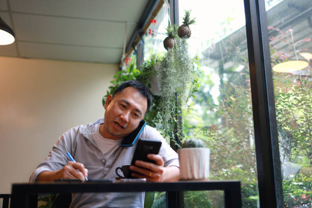 istock Mid adult man using smartphones in a cafe 1421202288