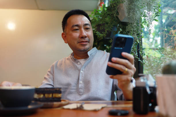 istock Mid adult man using smartphone in a cafe 1421202350