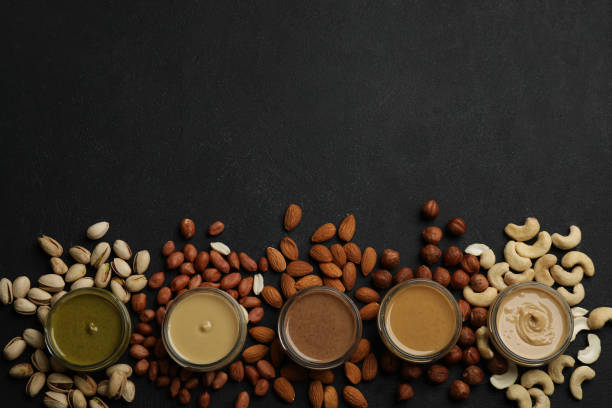 istock Jars with butters made of different nuts and ingredients on black table, flat lay. Space for text 1421202561