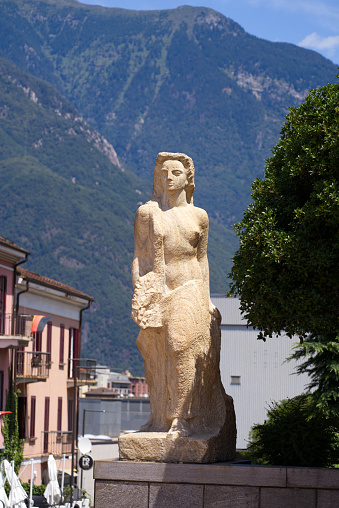Stone sculpture of a woman at railway station Bellinzona, Canton Ticino, on a sunny summer day. Photo taken July 4th, 2022, Bellinzona, Switzerland.