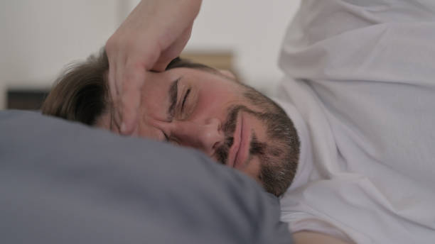 istock Portrait of Young Man having Headache while Sleeping in Bed 1421205468