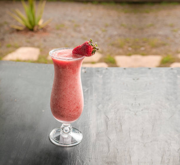 frullato di fragole sano in vetro su legno scuro. frappè alla fragola su legno scuro con sfondo sfocato. primo piano delizioso frullato di fragole con pezzi di fragola su legno. - freaking foto e immagini stock