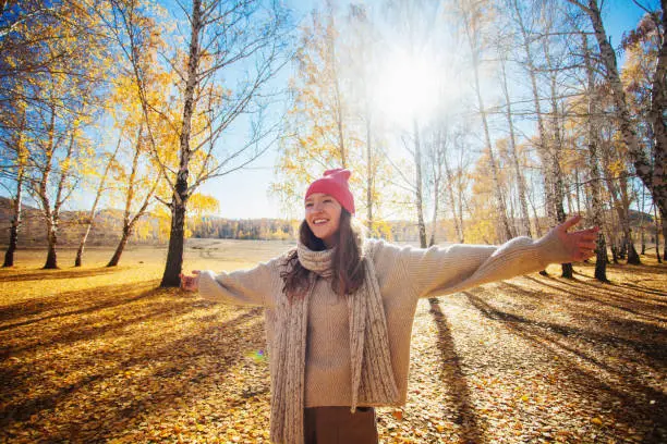 Happy young woman at the autumn park. Pretty teen girl expressing freedom outdoor at fall